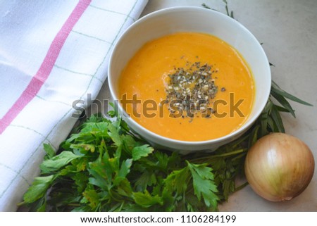Homemade creamy butternut squash pumpkin soup sprinkled with dried basil and sesame with fresh parsley and spring onion