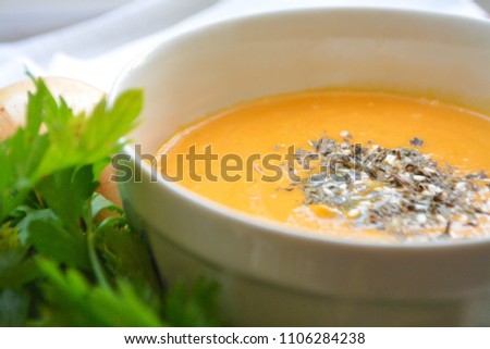Homemade creamy butternut squash pumpkin soup sprinkled with dried basil and sesame with fresh parsley and spring onion