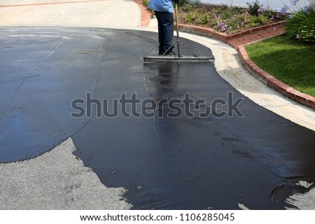 Private drive way, street rehabilitation and slurry seal project finished with crews expertly applying the slurry seal. Re-surfaced Cul-de-sac shown with unidentifiable crew working


 Royalty-Free Stock Photo #1106285045