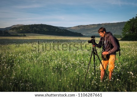 Photographer takes a pictures of a field with chamomiles 
