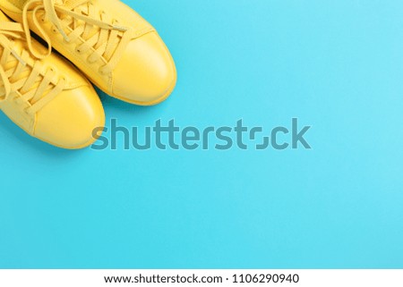 Pair of yellow shoes on blue background. Trendy summer color. Looking like the sun in the sky.