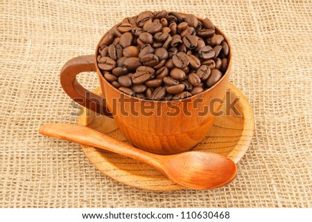 Roasted coffee beans with wooden cup on jute hessian background