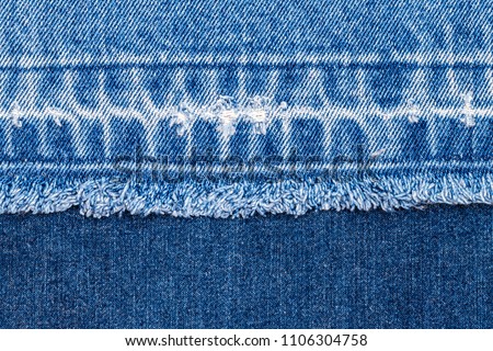 Denim blue jeans fabric frame. Bleached denim fabric with fringe edge  on blue denim background, text place, copy space. Worn Jeans Casual Double Color patch