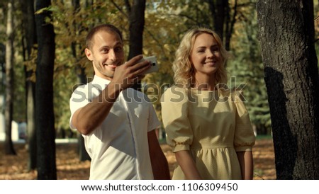 Smiling couple making selfie in autumn park