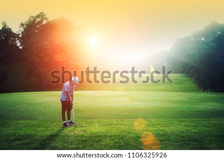 Golf kid. Asian boy practicing golf ball putt in the evening golf course at Thailand