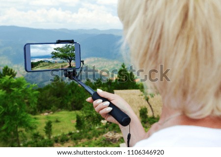 Female traveller make a panoramic photo from the mountain to her phone for Instagram or other social networks. Travel concept. Summer vacation.