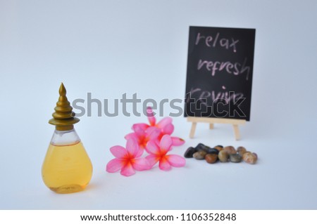 Essential oil with plumeria flowers, stones and black board with word relax refresh revive is writing on it as background isolated on white background.
