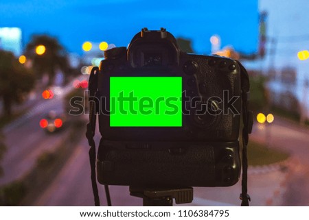 Close-up of DSLR Camera capturing on colorful light abstract circular bokeh background,Night time,Mockup image of with blank screen,DSLR on Tripod,Green screen.