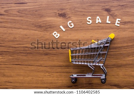 Mini model of Shopping cart or supermarket trolley with super sale text isolated on brown wooden background.  Modern lifestyle and e-commerce shopping sale festival in concept.