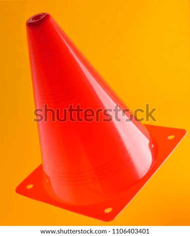 Orange cone, road barrier isolated on a yellow background.