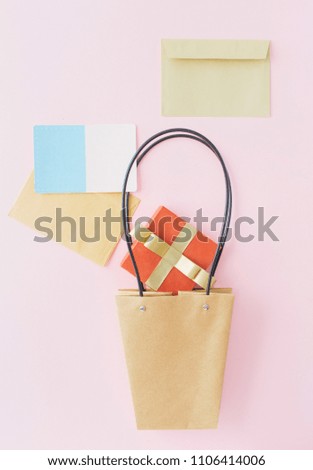 Creative layout made of paper bag, red gift box, envelope and blank greeting card on pink pastel background. Flat lay. Top view. Minimal celebration concept
