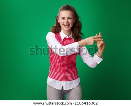happy modern student woman in a red waistcoat showing hashtag gesture isolated on green background