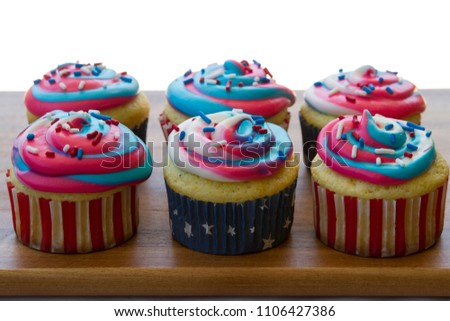 Happy 4th of July conceptual image with homemade blue red white color cupcakes on rustic wooden cutting board.
