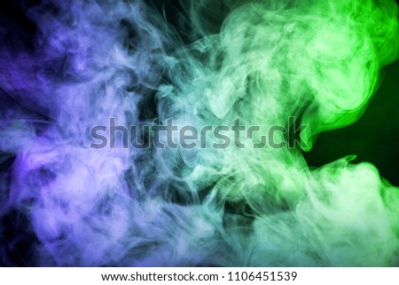 Thick colorful blue and green smoke on a black isolated background. Background from the smoke of vape
