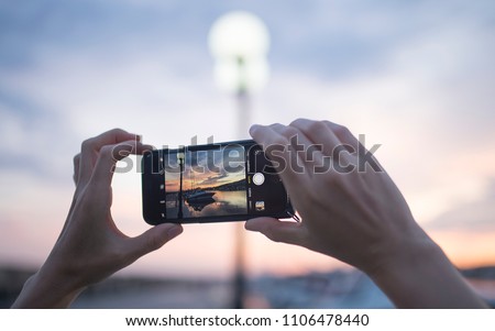 Woman using smart phone take a photo sunset view Royalty-Free Stock Photo #1106478440