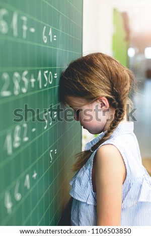 At school - Sad girl tries to count on the blackboard