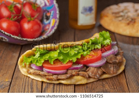 Delicious fresh homemade sandwich with chicken burspit roasted meat, tomato, onions and lettuce on wooden board on dark wooden table. Doner kebab. Healthy food concept.