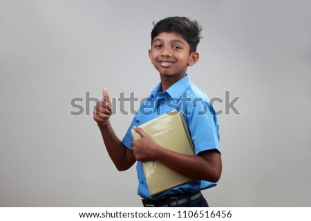 Portrait of a school boy wearing uniform holds note books in hand