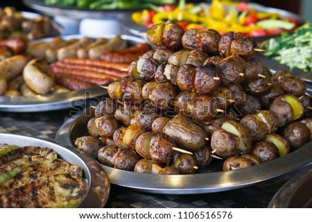 Dinner table with meat grill, roast new potatoes, vegetables, salads, sauces, snacks and lemonadeá Grilled sausage, mushrooms. Stock Photo