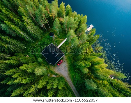 Aerial view of wooden cottage in green pine forest by the blue lake in rural summer Finland Royalty-Free Stock Photo #1106522057