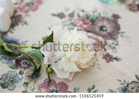 Table setting decor with cutlery, plates and glasses, decorated with a bouquet of peonies, rose petals and candles on the balcony or veranda of a restaurant or hotel for a romantic wedding dinner  