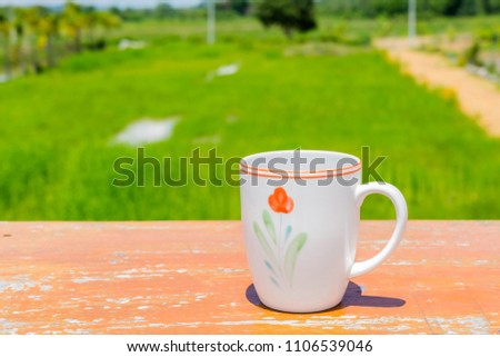 beautiful white coffee cup on wooden table with gree garss nature background 