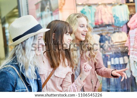 Group of female friends admires fashion in boutique storefront