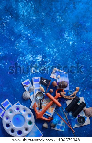Artist workplace with watercolor sketches, seashells, wooden anchor and compass on a navy blue background with copy space. Creative travel and painting concept