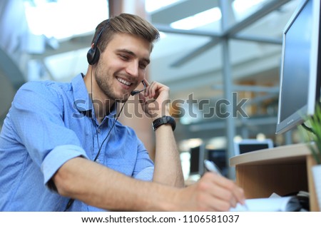 Smiling friendly handsome young male call centre operator Royalty-Free Stock Photo #1106581037