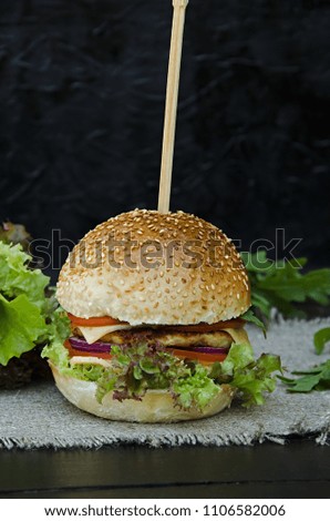 American hamburger burger with vegetables, chicken cutlet, salad, cheese and barbecue sauce. Fast food.