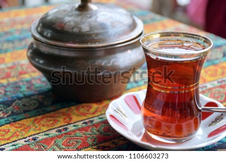 Black Turkish tea with traditional pot of sugar set of traditional glass tea of Turkey on colorful tradition clothing table, old original set of Turkish tea  concept  