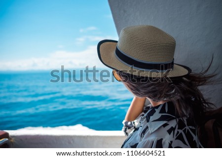traveler young woman in casual dress with hat and hair wind blowing have sea background