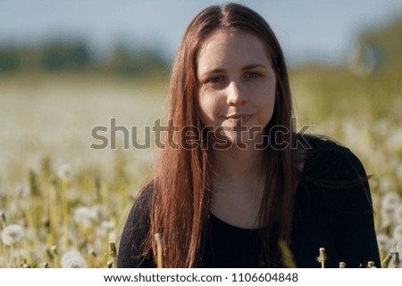 Pretty young woman holding dandelion in summer park