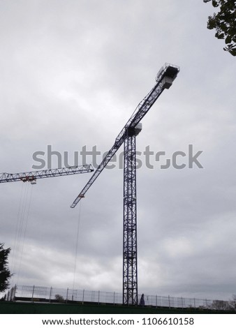 tall crane structures against cloudy sky background
					