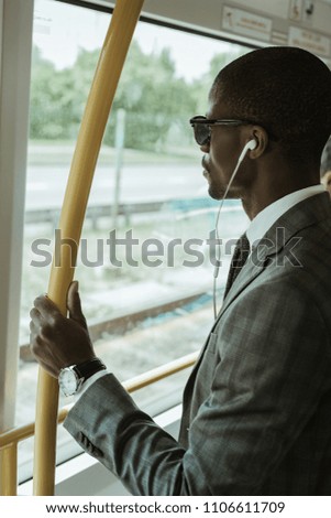 African american confident businessman listening to music while going to work by train