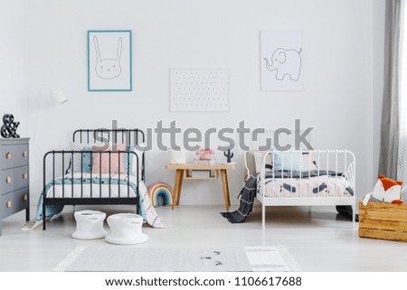 Wooden table between black and white bed in children bedroom interior with posters. Real photo