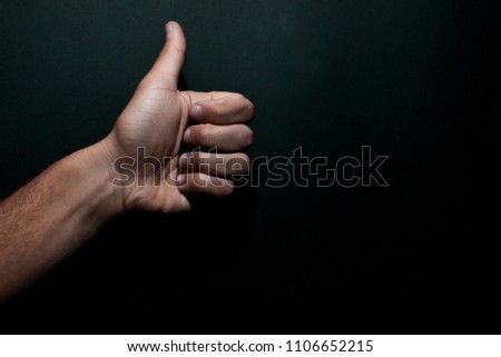 hand with a raised thumb, picture of a hand on a black background
