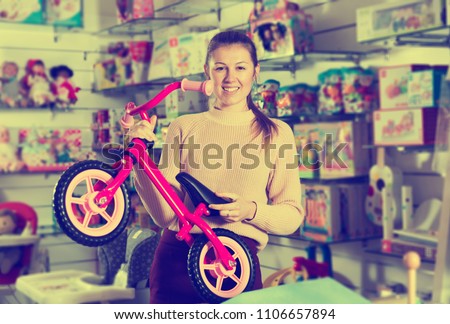 Female buyer choosing sport toy run bicycle in the shop for kids 