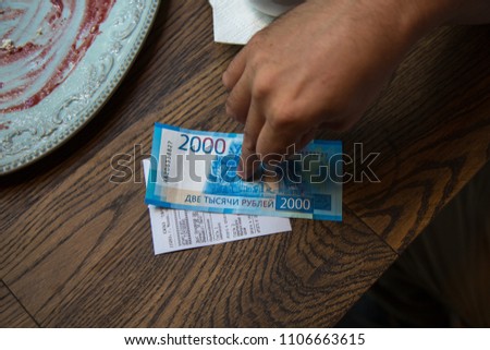 Man put finger on New 2000 rubles banknote in  in cafe.
