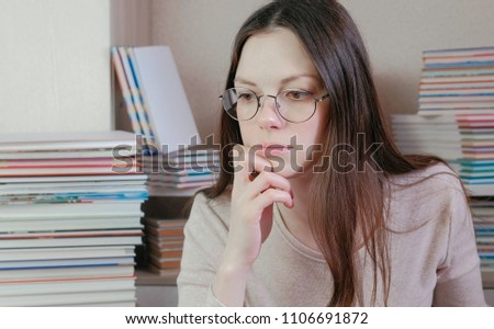Young brunette woman in glasses is thinking.