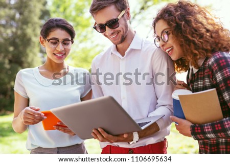 Day off together. Pleased young man holding his laptop and discussing a new project with his groupmates Royalty-Free Stock Photo #1106695634