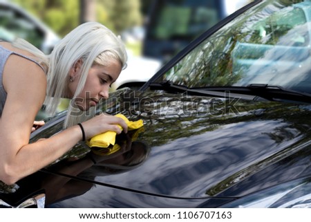 pretty girl cleaning the hood of a car