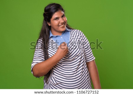 Studio shot of young overweight beautiful Indian businesswoman against chroma key with green background