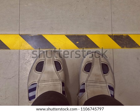 Foot on the floor with black and yellow line