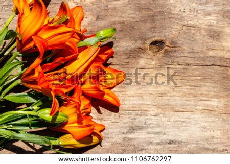 Orange lilies on rustic wooden background. Top view, copy space