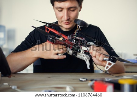 Photo of engineer mending square copter at table