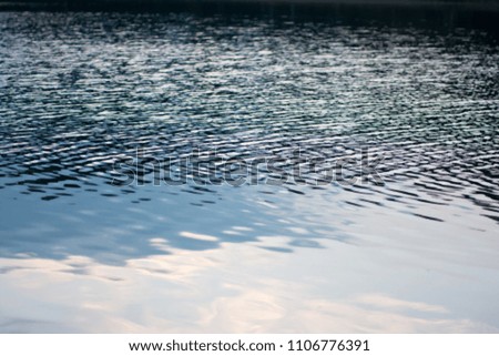 dark blue water surface with smooth surface in front and blurred rippled surface at the back