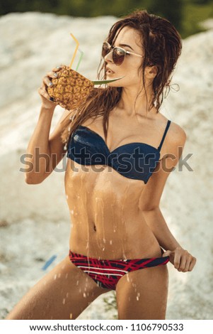 Romantic girl with long hair drinking pineapple cocktail with eyes closed. Outdoor shot of adorable young woman in enjoying lunch in at resort. Selective focus