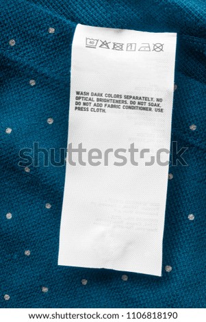 Care clothes label on blue polka dots textile background closeup