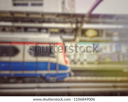 Blurred image of BTS sky train station with unclear background. day time and the train arrive.  transportation and connection concept. vintage tone and light effect filter.